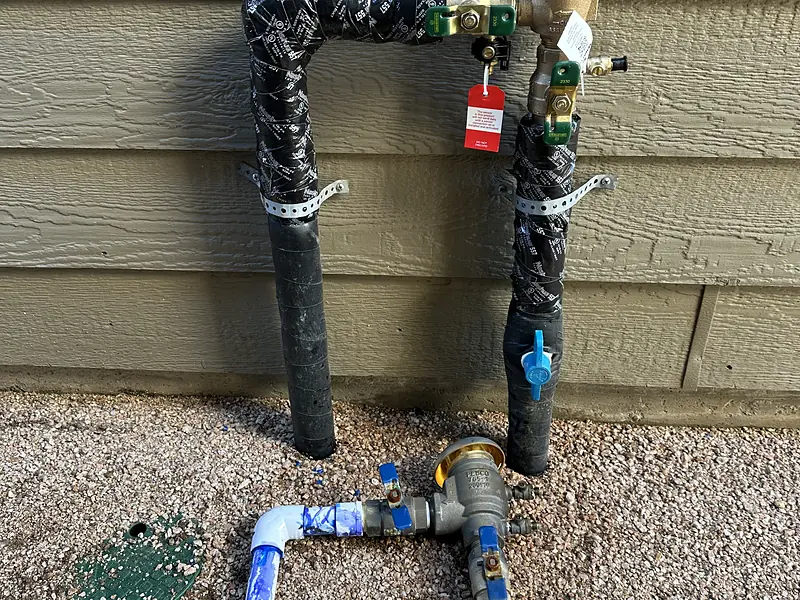 Backflow preventer wrapped with insulation on a house with siding