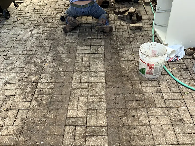 Crew relaying paving stones over a repaired water line