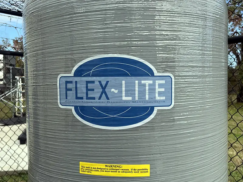 Large fiberglass pressure tank in a fenced enclosure