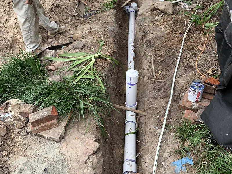 Crew laying new PVC sewer pipe in a trench