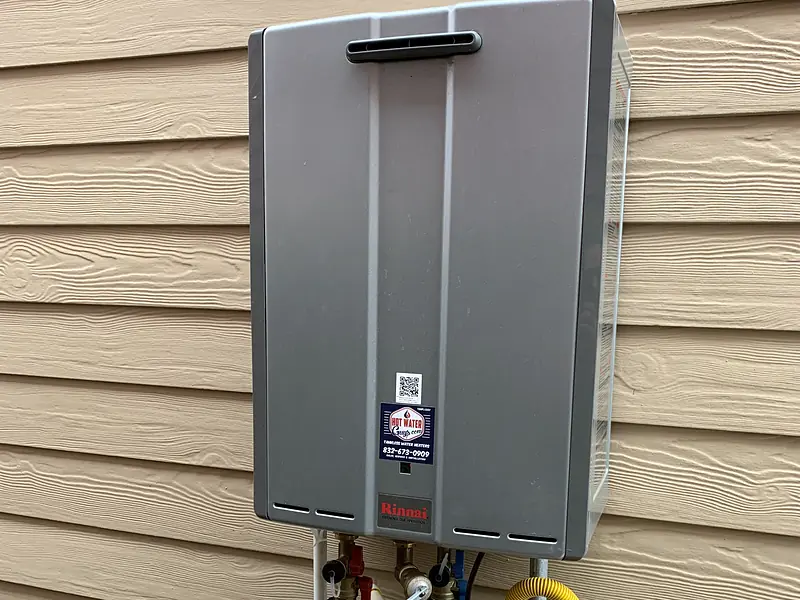 Outdoor tankless water heater mounted on siding with gas and water lines