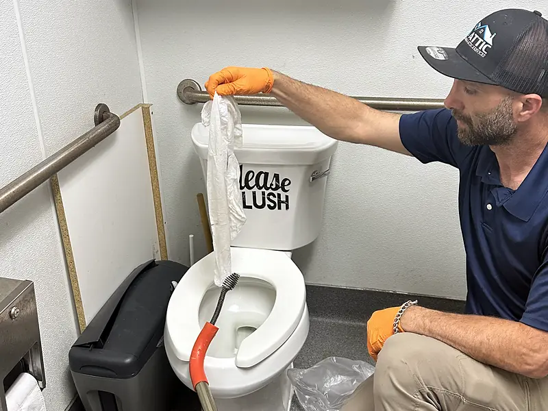 Royal Flush Affordable Plumbing plumber working on a toilet in a commercial restroom