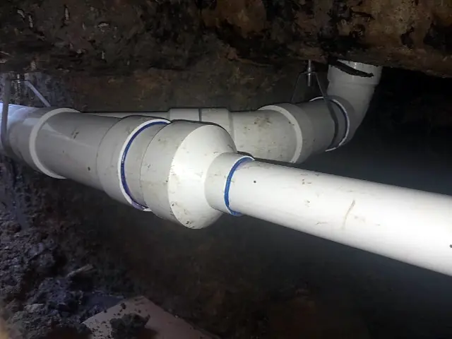 New PVC drain line hung on hangers inside a tunnel under a slab