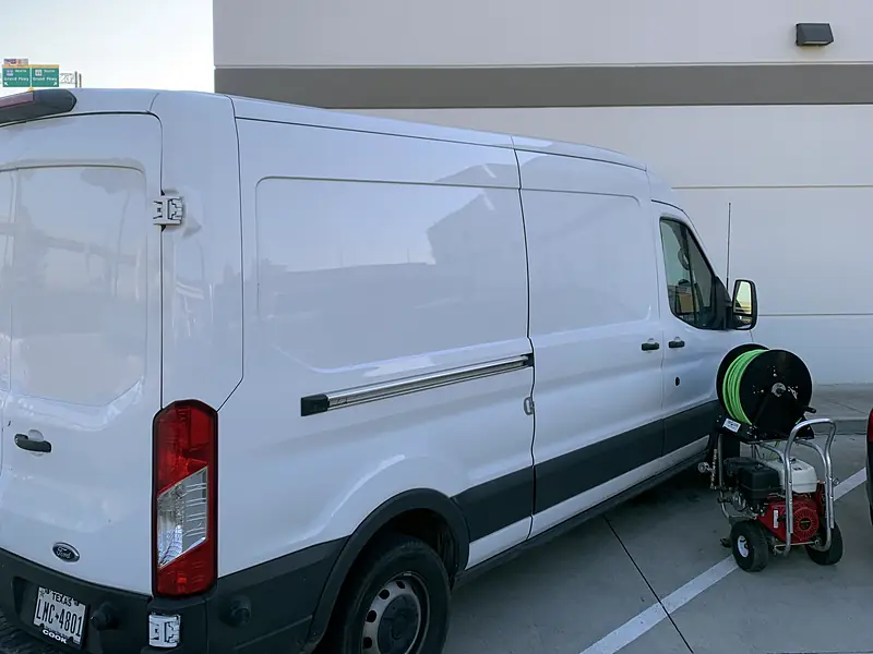 Royal Flush Affordable Plumbing van parked at a restaurant with a hydro jetter beside it
