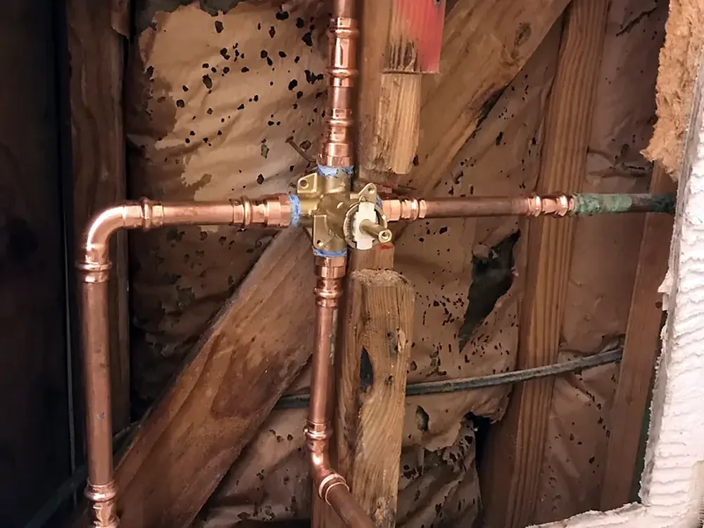 Shower valve connected with new copper pipe and fittings inside an open wall, replacing corroded galvanized piping